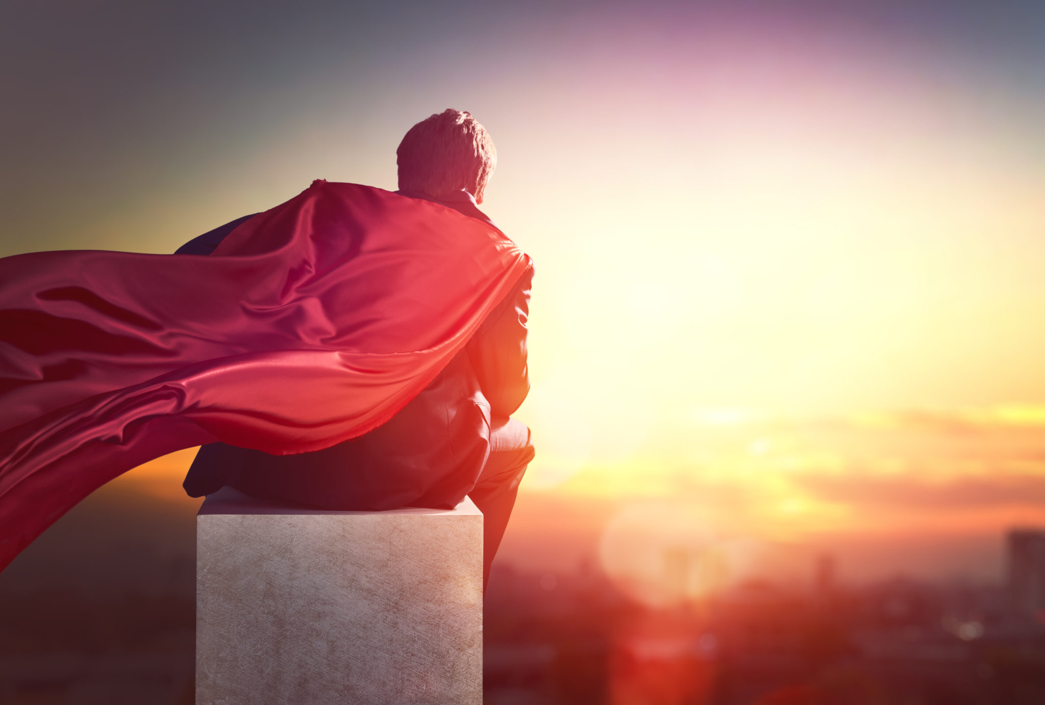 superhero businessman looking at city skyline at sunset. the concept of success, leadership and victory in business.